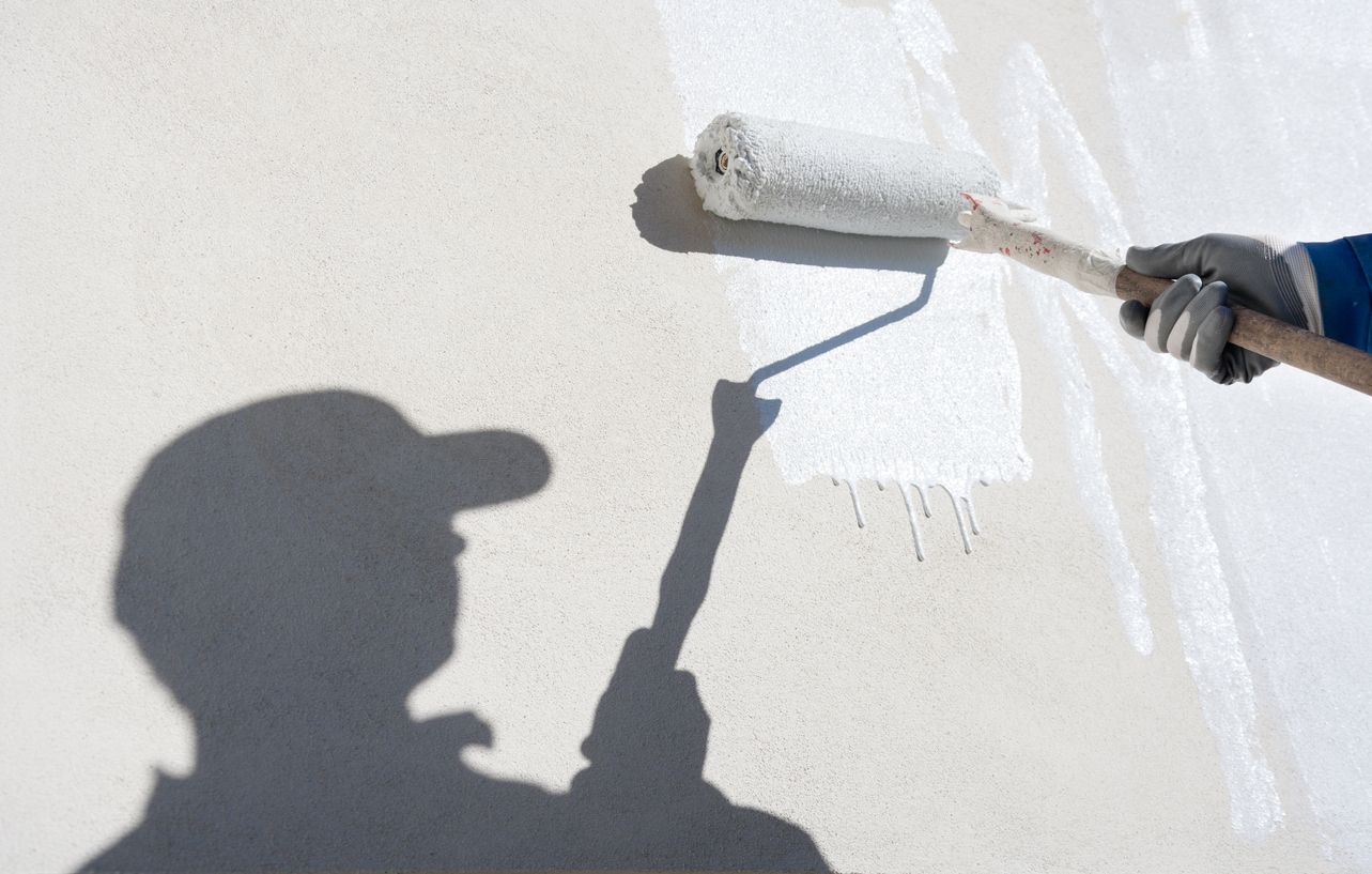 De Rizzo Painting Service Perth - man's shadow against cream external wall, painting white with a paint roller